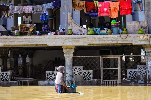 A woman wades through floodwaters as evacuees (top) take shelter in a mosque at Meunasah Jok village in Lhoksukon, North Aceh on January 5, 2022. (Photo by Azwar Ipank/AFP Photo)