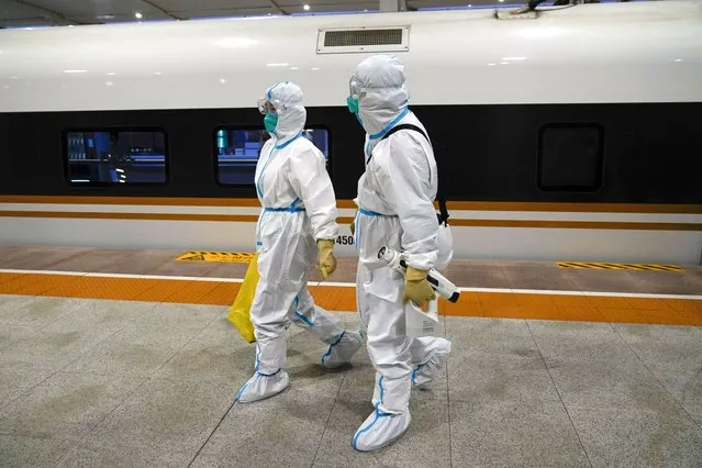 Two workers in protective gear walk way from a train car designated for Olympic workers after disinfecting it at a train station ahead of the 2022 Winter Olympics, Thursday, January 27, 2022, in Zhangjiakou, China. (Photo by Jae C. Hong/AP Photo)