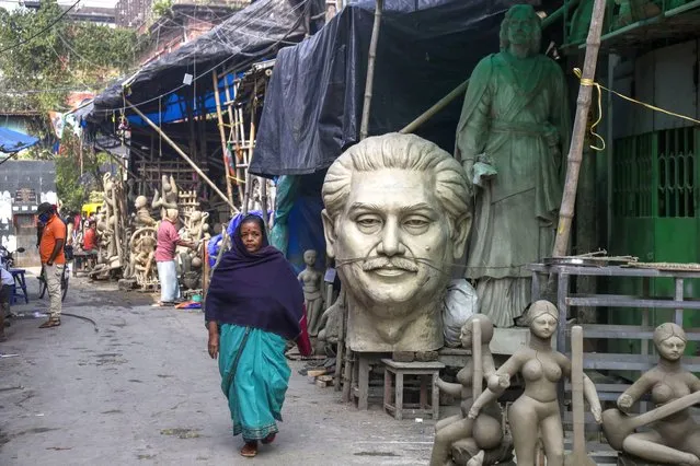 A woman walks past a bust of Sheikh Mujibur Rahman, founding father of Bangladesh at Kumortuli, the potter's place in Kolkata, India, Monday, January 17, 2022. (Photo by Bikas Das/AP Photo)