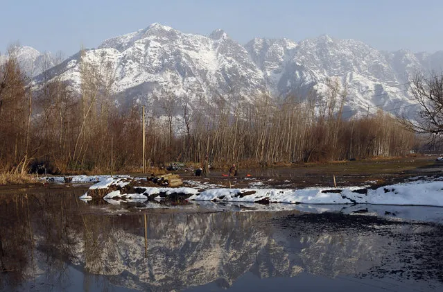 Framed by the Zabarwan Hills, a Kashmiri man sits by Dal Lake on a sunny day, in Srinagar January 2, 2011. (Photo by Danish Ismail/Reuters)