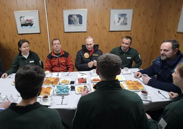 Russian President Vladimir Putin, center, and Prime Minister Dmitry Medvedev, second left, listen to the employees of the “Omega” field base in the Russian Arctic National Park on the Franz Josef Land archipelago, Russia, Wednesday, March 29, 2017. (Photo by Alexei Druzhinin, Sputnik, Kremlin Pool Photo via AP Photo)