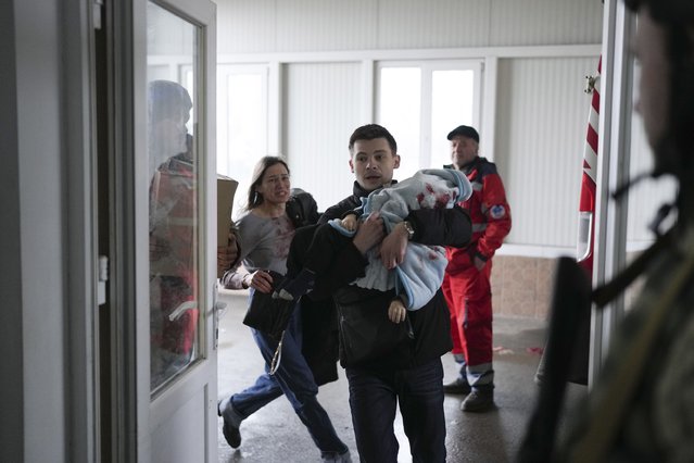 Marina Yatsko, left, runs behind her boyfriend Fedor carrying her 18 month-old son Kirill who was killed in shelling, as they arrive at a hospital in Mariupol, Ukraine, Friday, March 4, 2022. (Photo by Evgeniy Maloletka/AP Photo)