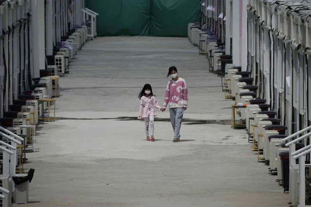 Patients walk along mobile cabins COVID-19 isolation facilities in the San Tin area of Hong Kong, Friday, March 11, 2022. (Photo by Kin Cheung/AP Photo)