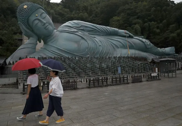 Women walk past the reclining Buddha statue as they visit the Nanzo-in temple in Sasaguri, Fukuoka Prefecture, southwestern Japan, Monday, September 30, 2019. The reclining Buddha statue, known as either Nehanzo or Shaka Nehan is 41 meters long, 11 meters high, and weighs nearly 300 tons. (Photo by Christophe Ena/AP Photo)