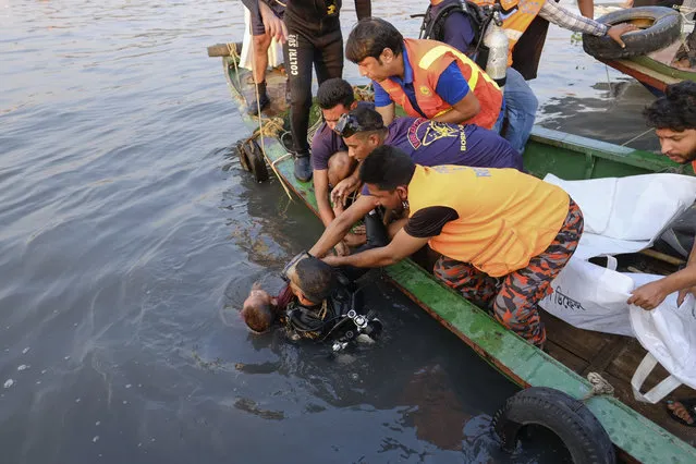 Rescuers recover the body of a child after a cargo vessel hit a ferry carrying dozens of people in Narayanganj, outside Dhaka, Bangladesh, Sunday, March 20, 2022. Six bodies were recovered, it is not clear immediately how many are still missing. (Photo by Mahmud Hossain Opu/AP Photo)