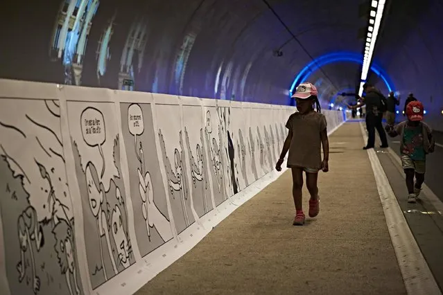 A child walks along a comic strip displayed along the tunnel of Croix-Rousse in Lyon on May 21, 2016. This 1,6 kilometer fresco realized by 200 French and Spanish students  which entered the Guinness Book of records, inaugurates today the 11th edition of the “Lyon BD Festival” (Lyon's comic book festival). (Photo by Jean-Philippe Ksiazek/AFP Photo)