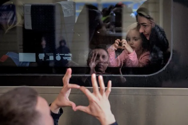 Ukrainian Nicolai, 41, says goodbye to his daughter Elina, 4, and his wife Lolita, on a train bound for Poland fleeing from the war at the train station in Lviv, western Ukraine, Friday, April 15, 2022. (Photo by Emilio Morenatti/AP Photo)