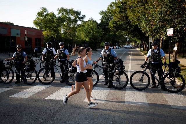 Women jog as police officers block a road during a protest in support of Palestinians in Gaza on the sidelines of the Democratic National Convention in Chicago, on August 21, 2024. (Photo by Marco Bello/Reuters)