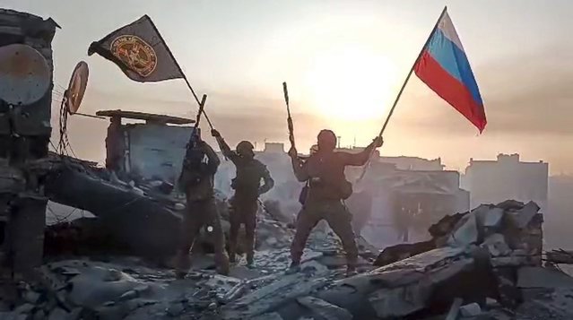 In this grab taken from video released by Prigozhin Press Service on Saturday, May 20, 2023, Yevgeny Prigozhin's Wagner Group military company members wave a Russian national and Wagner flag atop a damaged building in Bakhmut, Ukraine. The head of the Russian private army Wagner claims his forces have taken control of the city of Bakhmut after the longest and most grinding battle of the Russia-Ukraine war, but Ukrainian defense officials have denied it. In a video posted on Telegram, Prigozhin said the city came under complete Russian control at about midday Saturday. (Photo by Prigozhin Press Service via AP Photo)