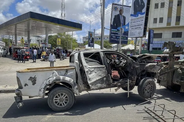 A destroyed vehicle is removed from the scene after a suicide bomb attack at a checkpoint near the airport in Mogadishu, Somalia, Wednesday, May 11, 2022. Somali police say several people have been killed in the explosion which happened as presidential candidates were heading into the heavily fortified airport area to address lawmakers ahead of Sunday's vote for president. (Photo by Farah Abdi Warsameh/AP Photo)