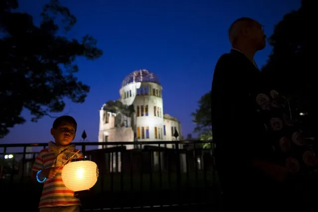 A boy holds a paper lantern in front of the Atomic Bomb Dome during a procession commemorating the victims of the atomic bombing in Hiroshima, western Japan, August 5, 2015. (Photo by Thomas Peter/Reuters)