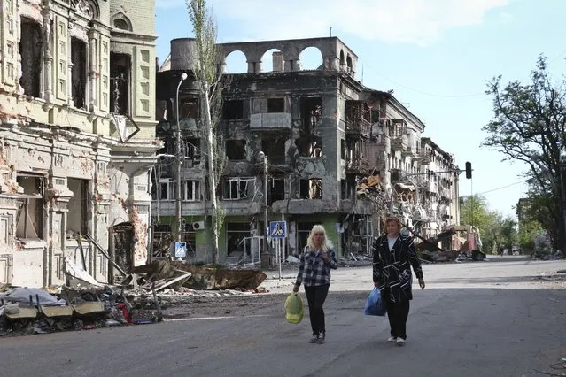 Women walk among buildings destroyed during fighting in Mariupol, in territory under the government of the Donetsk People's Republic, eastern Ukraine, Wednesday, May 25, 2022. (Photo by AP Photo/Stringer)