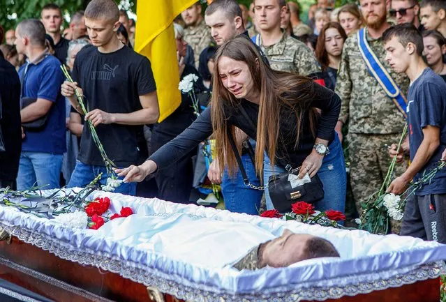 A mourner reacts as she places flowers on the coffin of Denis Kofel, a Ukrainian serviceman who was killed during Russia's invasion, during his funeral in Uzhhorod, Zakarpattia region, Ukraine on May 30, 2022. (Photo by Serhii Hudak/Reuters)