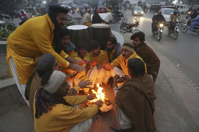 Pakistani street performers sit around a fire to keep themselves warm during a chilly evening in Lahore, Pakistan, Saturday, December 28, 2019. Different cities of Pakistan experiencing an extreme cold weather. (Photo by K.M. Chaudary/AP Photo)