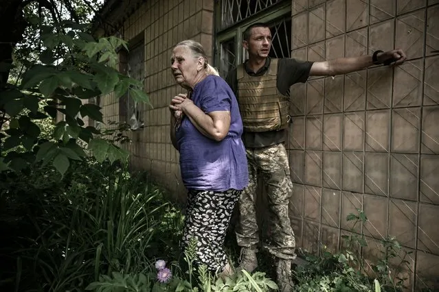 An elderly woman reacts as Ukrainian servicemen help her to take cover during an artillery duel between Ukrainian and Russian troops in the city of Lysychansk, eastern Ukrainian region of Donbas, on June 11, 2022. (Photo by Aris Messinis/AFP Photo)