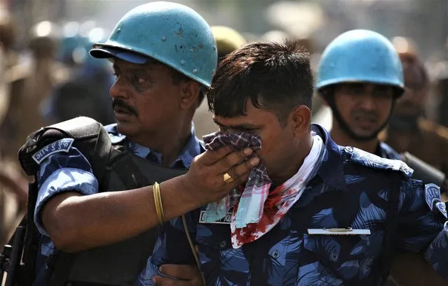 A policeman is being helped by his colleagues after he was injured during a protest against a Bharatiya Janata Party (BJP) member Nupur Sharma for her comments on Prophet Mohammed, in Prayagraj, India on June 10, 2022. (Photo by Ritesh Shukla/Reuters)