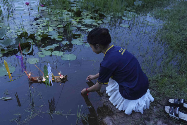 A local young girl releases food onto a pond as she gathers for a traditional ceremony to send ancestors back after the celebration of Pchum Ben, or Ancestors' Day in the outskirts of Phnom Penh, Cambodia, Thursday morning, October 3, 2024. (Photo by Heng Sinith/AP Photo)