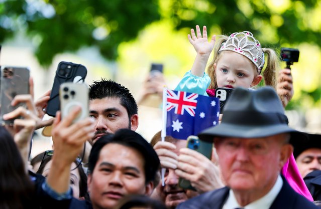 A girl waves as wellwishers wait outside the church during Britain's King Charles and Queen Camilla's visit to St. Thomas's Anglican Church, on October 20, 2024 in Sydney, Australia. The King's visit to Australia will be his first as Monarch, and CHOGM in Samoa will be his first as Head of the Commonwealth. (Photo by Toby Melville-Pool/Getty Images)