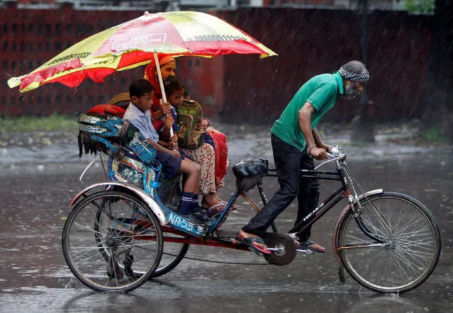A woman and her children ride in a rickshaw during heavy rains in Chandigarh, India August 21, 2017. (Photo by Ajay Verma/Reuters)