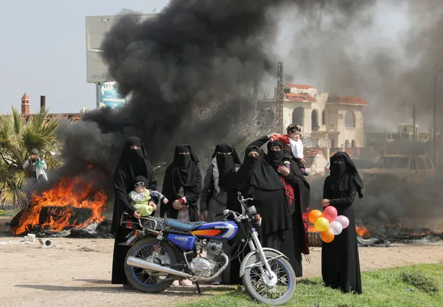 Women stand near burning tires during a protest against the agreement on joint Russian and Turkish patrols, at M4 highway in Idlib province, Syria, March 15, 2020. (Photo by Khalil Ashawi/Reuters)