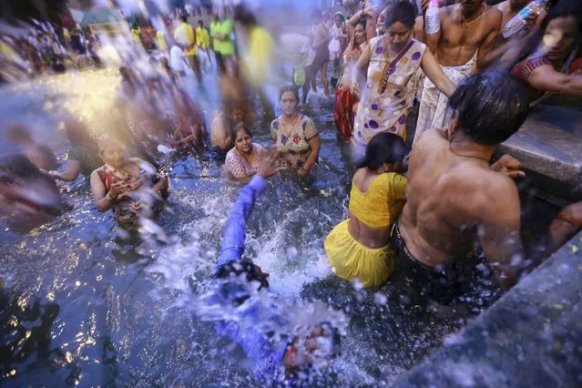 A Hindu devotee slips as others pray while standing in the Godavari river during Kumbh Mela or the Pitcher Festival in Nashik, India, August 28, 2015. (Photo by Danish Siddiqui/Reuters)