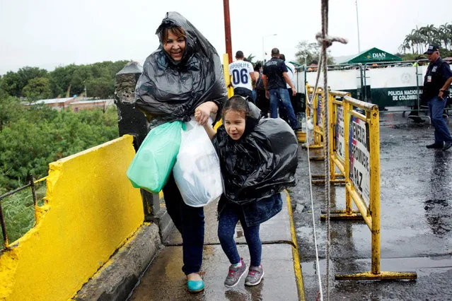 A woman and a child use plastic bags to take cover from the rain as they cross the Colombian-Venezuelan border over the Simon Bolivar international bridge after shopping, in San Antonio del Tachira, Venezuela, July 16, 2016. (Photo by Carlos Eduardo Ramirez/Reuters)