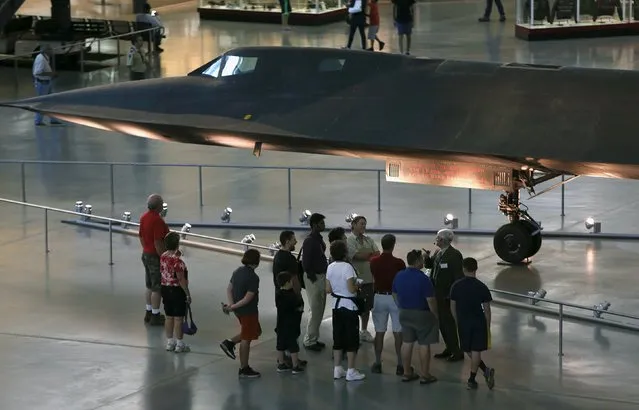 A tour group gathers under a Lockheed SR-71 Blackbird at the Udvar-Hazy Smithsonian National Air and Space Annex Museum in Chantilly, Virginia August 28, 2015. The SR-71 was a long-range spy plane that was in use from 1964 to 1998 and designed to operate at three times the speed of sound. (Photo by Gary Cameron/Reuters)