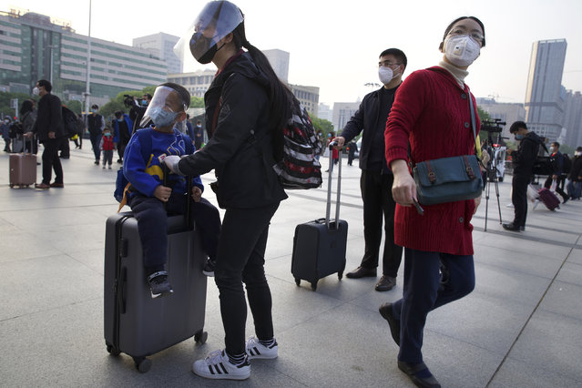 Passengers wearing face masks and face shields to protect against the spread of coronavirus gather outside of Hankou train station after of the resumption of train services in Wuhan in central China's Hubei Province, Wednesday, April 8, 2020. (Photo by Ng Han Guan/AP Photo)