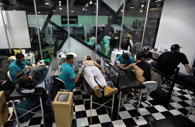 Tattoo artists work on clients during the Tattoo Week SP 2016 in Sao Paulo, Brazil, July 23, 2016. (Photo by Paulo Whitaker/Reuters)