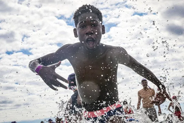 A boy plays in the ocean on the beach of Deauville, northwestern France, on August 24, 2022, as part of the “Days of the Forgotten of the Holidays” campaign organised by French NGO Secours Populaire. Some 5000 children from the Ile-de-France region whose families are unable to afford to go on holidays were taken on a trip to Deauville as part of the Secours Populaire's initiave. (Photo by Lou Benoist/AFP Photo)
