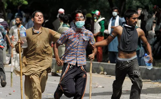 Pakistani protesters help escort their injured colleague to an ambulance during a protest near prime minister's home in Islamabad, Pakistan on Sunday, August 31, 2014. Pakistani police clashed with scattered pockets of anti-government protesters trying to advance on the prime minister's residence after a night of violence that saw hundreds wounded and the first death in more than two weeks of demonstrations. (Photo by Anjum Naveed/AP Photo)
