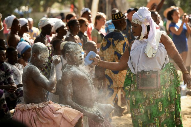A devotee pours powder on participants as they take part in the annual celebration of the Voodoo festival in Ouidah, Benin on January 9, 2025. (Photo by Charles Placide Tossou/Reuters)