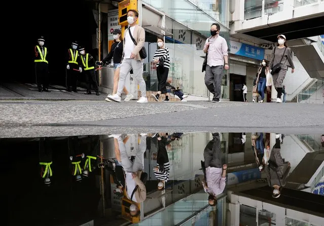 Pedestrians wearing protective masks are seen reflected in a puddle as they walk through a quiet street, following the outbreak of the coronavirus disease (COVID-19), Tokyo, Japan, May 4, 2020. (Photo by Kim Kyung-Hoon/Reuters)