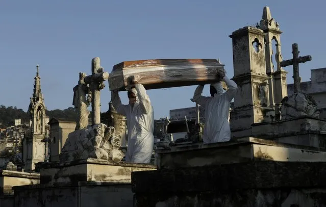 Gravediggers carry the coffin of Antonia Rodrigues who passed away from the coronavirus disease (COVID-19), during her funeral in Rio de Janeiro, Brazil, May 18, 2020. (Photo by Ricardo Moraes/Reuters)