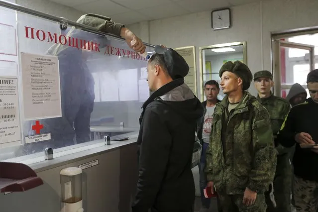 A Russian officer checks the temperature of recruits as they lineup to be registered at a military recruitment center in Volgograd, Russia, Saturday, September 24, 2022. (Photo by AP Photo/Stringer)
