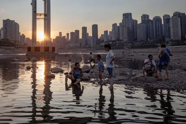 People sit on the dry riverbed of the Jialing river, a tributary of the Yangtze, that is approaching record-low water levels during a regional drought in Chongqing, China on August 20, 2022. (Photo by Thomas Peter/Reuters)