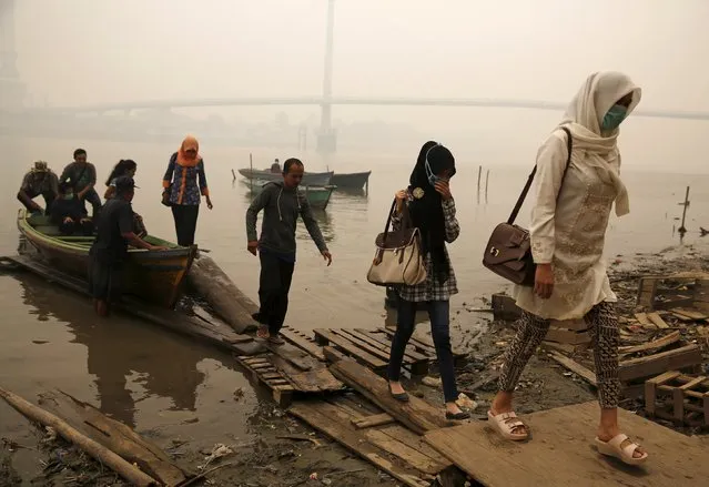 Workers walk up to the shore of a river basin after travelling on a boat as the haze shrouded Batanghari River in Jambi, on Indonesia's Sumatra island, September 15, 2015. Indonesian President Joko Widodo called late on Monday for strong action against anyone caught lighting fires to clear forested land, as a worsening haze blanketed the north of the country and neighbouring Singapore and Malaysia. (Photo by Reuters/Beawiharta)