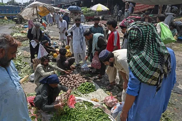 People buy vegetables at a local market in Lahore on August 30, 2022. Catastrophic monsoon floods in Pakistan have sent food prices skyrocketing, putting many staples out of the reach of the poor as the cash-strapped nation battles shortages. The floods have submerged a third of the country, killing more than 1,100 people and affecting over 33 million. (Photo by Arif Ali/AFP Photo)