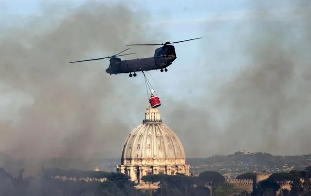 Smoke billows as an helicopter flies past the dome of St. Peter's Basilica on its way to extinguish a fire that broke out in the Monte Mario hill area, Rome, Tuesday, Aug. 23, 2016. (Photo by Massimo Percossi/ANSA via AP Photo)