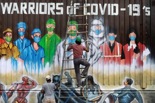A man gets off a ladder as he completes a mural paying tribute to “COVID-19 warriors” as India eases lockdown restrictions that were imposed to slow the spread of the coronavirus disease (COVID-19), in New Delhi, India, June 8, 2020. (Photo by Anushree Fadnavis/Reuters)