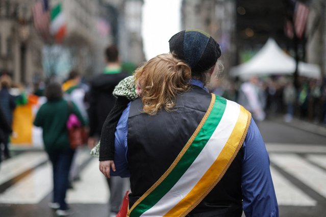 A person carries a child during the 264th annual St Patrick's Day parade on 5th Avenue in Manhattan in New York City, on March 17, 2025. (Photo by Mike Segar/Reuters)