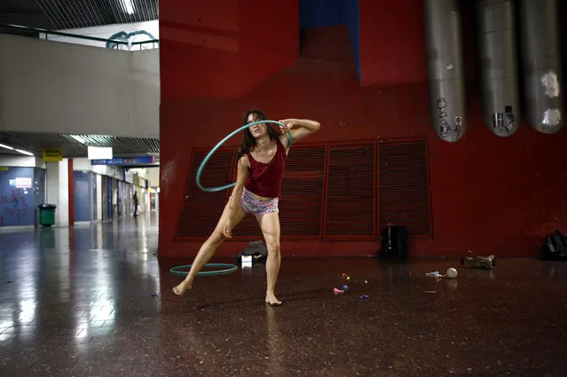 Stav Pinto, 24, uses a hula hoop as she practices her acrobatics skills during a weekly informal circus community meeting at the Central Bus Station in Tel Aviv, Israel July 1, 2019. Pinto employs her circus talents to teach life skills to special needs children. Pinto and her hula hoop take part in an informal circus group that meets on Monday evenings. “There's a magical air to the Central Bus Station that reminds me of a dark urban forest”, she said. “It's a place of adventure where you can meet a variety of people and be exposed to different cultures. Every time I walk through it, I can discover a new place that is completely different from the others”. (Photo by Corinna Kern/Reuters)