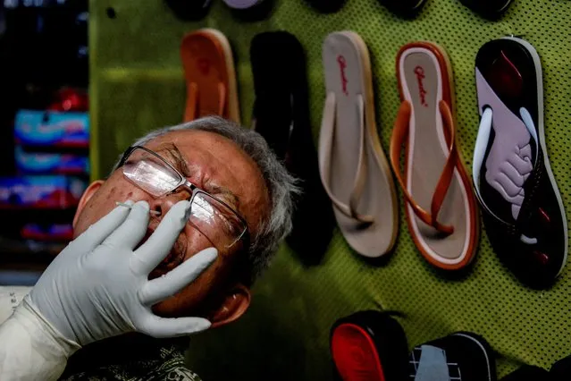 A vendor reacts as a healthcare worker in protective gear collects a swab sample to be tested for the coronavirus disease (COVID-19) at a traditional market in Jakarta, Indonesia, June 25, 2020. (Photo by Willy Kurniawan/Reuters)