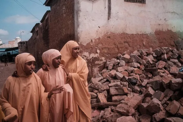 Girls dressed in local school uniform walk next to rubble along a street in Baidoa, Somalia, on November 9, 2022. After four consecutive failed rainy seasons, Somalia, Kenya and Ethiopia are in the midst of the worst period of drought for 40 years and with another poor rainy season is now likely to follow. Extreme drought has destroyed crops and led to the death of livestock. Combined with a high security threat from Al Shabaab that makes it hard to deliver aid, some 7 million Somalis, nearly half the population at risk of famine in Somalia. (Photo by Guy Peterson/AFP Photo)