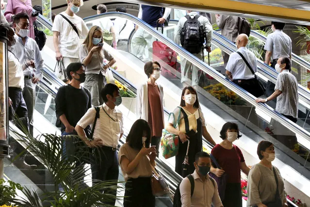 People wearing face masks to protect against the spread of the new coronavirus take an escalator at Yokohama station near Tokyo, Wednesday, July 22, 2020. (Photo by Koji Sasahara/AP Photo)