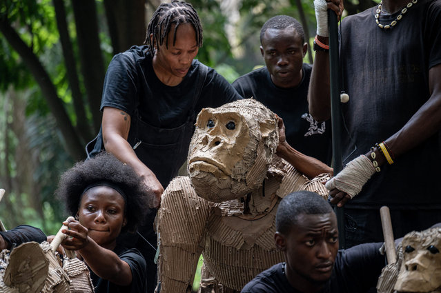 Puppeteer crouche next to a life size animal puppet, part of the Herds public art and climate action project are displayed in Kinshasa on April 9, 2025. A wildebeest, a gorilla and a giraffe were among the life-size puppets to begin a 20,000-kilometre (12,400-mile) trek across the globe Wednesday from the DR Congo capital, to raise awareness about migration due to climate change.The animals are part of The Herds project and aim to have crossed around 10 countries between central Africa and the Arctic by August. Their journey will take them through Nigeria, Senegal, Morocco, France and Norway, among other countries. (Photo by Hardy Bope/AFP Photo)