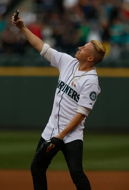 Rap star Macklemore takes a “selfie” photo just before throwing out the ceremonial first pitch prior to the game between the Seattle Mariners against the New York Yankees at Safeco Field on June 12, 2014 in Seattle, Washington. (Photo by Otto Greule Jr/Getty Images)