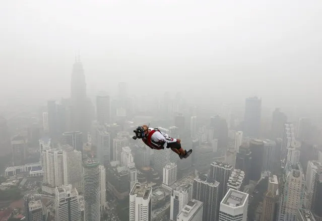 A BASE jumper leaps from the 300-metre high Kuala Lumpur Tower during the International Tower Jump in which more than 100 people take part, on a hazy day in Kuala Lumpur, Malaysia October 2, 2015. Slash-and-burn agriculture in neighbouring Indonesia has blanketed Malaysia and Singapore in a choking haze for weeks. (Photo by Olivia Harris/Reuters)