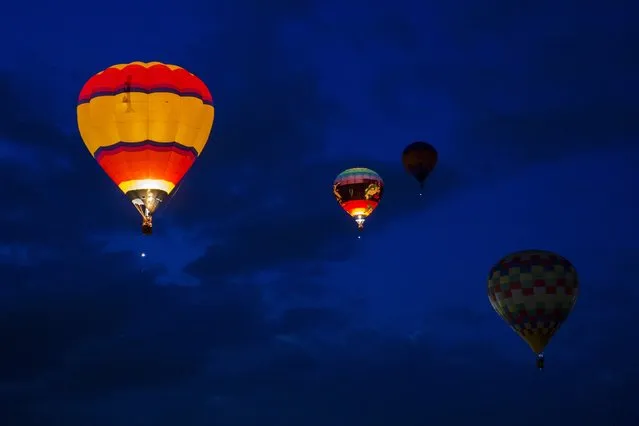 Hot air balloons drift in the sky as one is lit by flame after taking off on the first day of the 2015 Albuquerque International Balloon Fiesta in Albuquerque, New Mexico, October 3, 2015. (Photo by Lucas Jackson/Reuters)