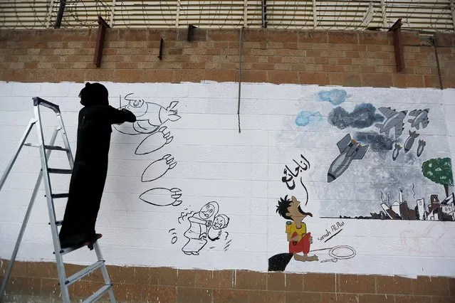 A pro-Houthi activist paints graffiti depicting Saudi-led air strikes on the wall of the Saudi embassy in Sanaa July 29, 2015. (Photo by Khaled Abdullah/Reuters)